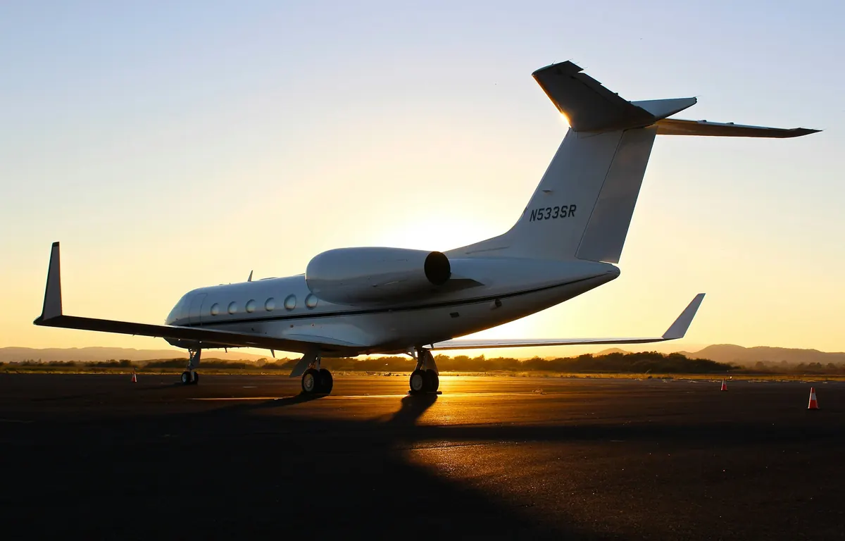 Private jet on the ramp against an orange sunset